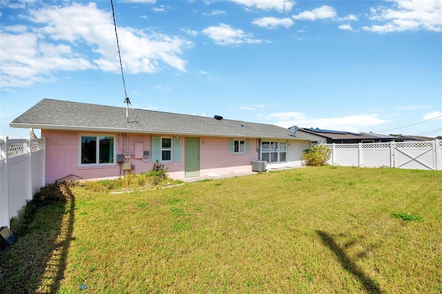 rear view of property featuring central air condition unit, a fenced backyard, concrete block siding, and a yard