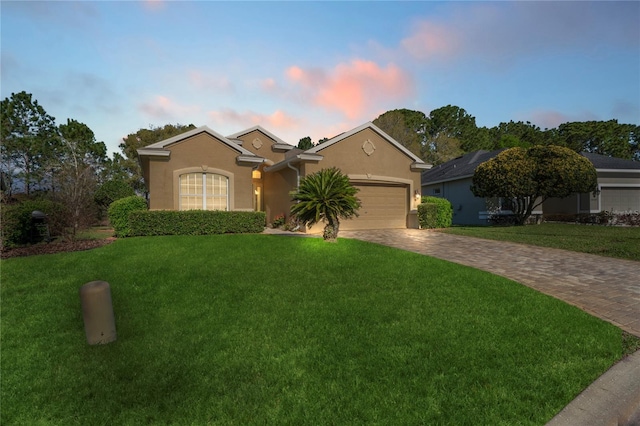 single story home with a garage, stucco siding, driveway, and a front lawn