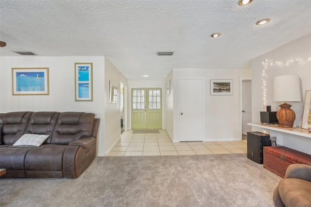 living area featuring light carpet, visible vents, a textured ceiling, and light tile patterned floors