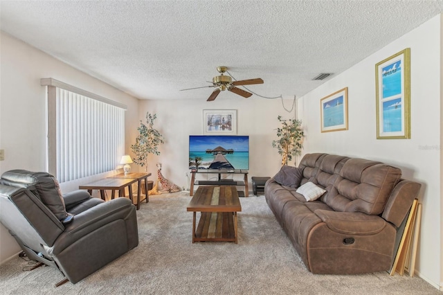 carpeted living area featuring a textured ceiling, visible vents, and a ceiling fan