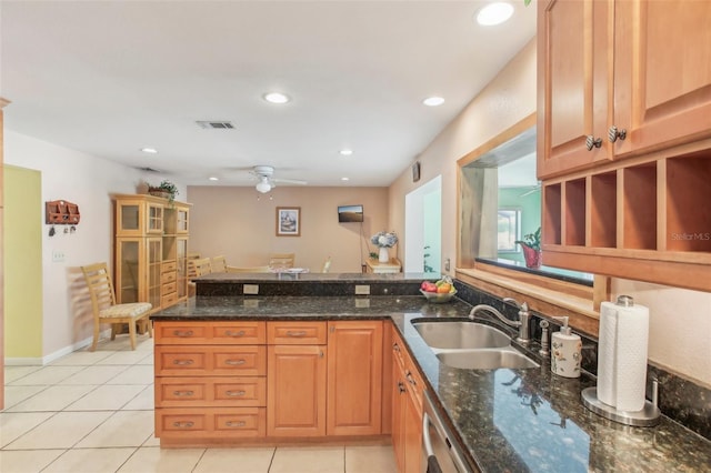 kitchen with light tile patterned floors, dark stone counters, and a sink