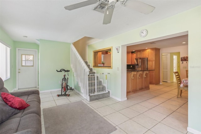 living area featuring light tile patterned floors, baseboards, stairway, and ceiling fan