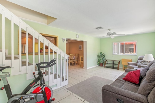 living room with light tile patterned floors, visible vents, stairway, ceiling fan, and baseboards