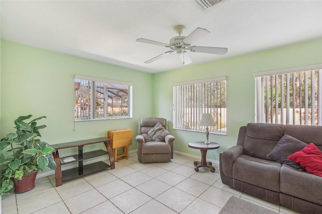 living area featuring light tile patterned floors, visible vents, a ceiling fan, and baseboards