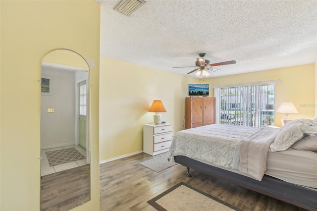 bedroom featuring a textured ceiling, wood finished floors, visible vents, and baseboards