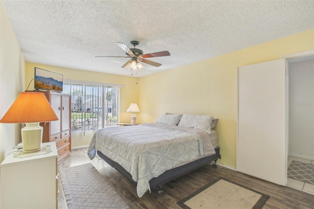 bedroom with dark wood-style floors, access to exterior, ceiling fan, and a textured ceiling