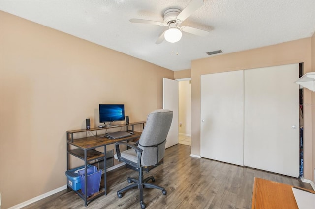 office area featuring visible vents, ceiling fan, baseboards, and wood finished floors