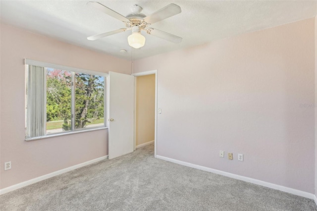 unfurnished room with carpet, a ceiling fan, and baseboards