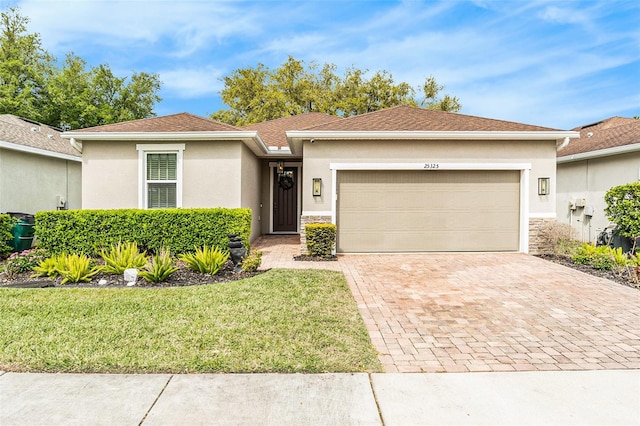 ranch-style home with a garage, decorative driveway, a front yard, and stucco siding