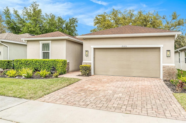 single story home featuring roof with shingles, an attached garage, stucco siding, stone siding, and decorative driveway