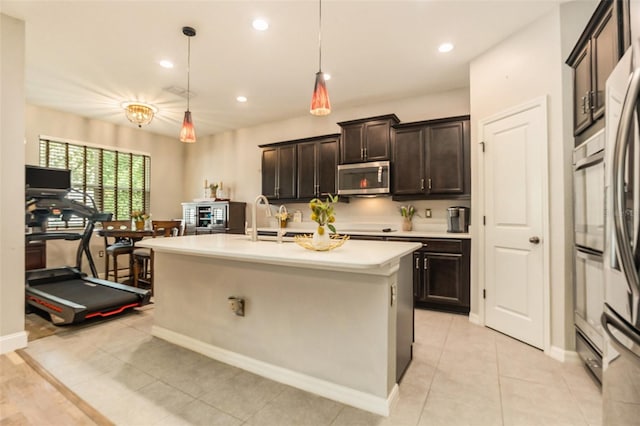 kitchen featuring a center island with sink, light countertops, light tile patterned floors, recessed lighting, and stainless steel appliances