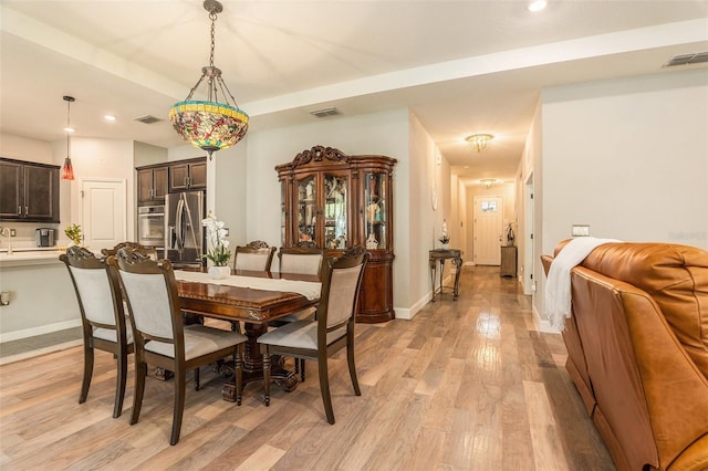 dining room featuring light wood-type flooring, visible vents, and baseboards