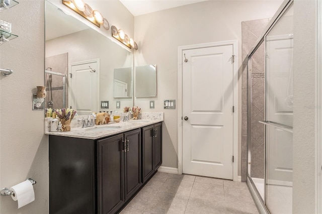 full bathroom with tile patterned flooring, a shower stall, baseboards, double vanity, and a sink