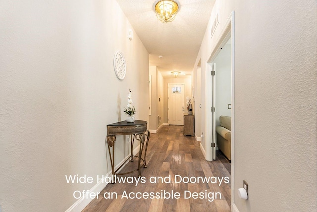 corridor featuring visible vents, dark wood-type flooring, baseboards, and a textured wall