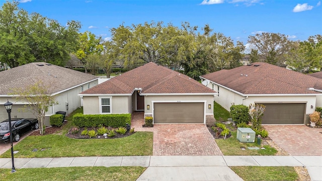 ranch-style home with a front lawn, decorative driveway, a garage, and stucco siding