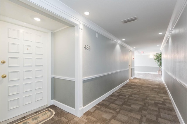 hallway with visible vents, ornamental molding, dark colored carpet, and recessed lighting