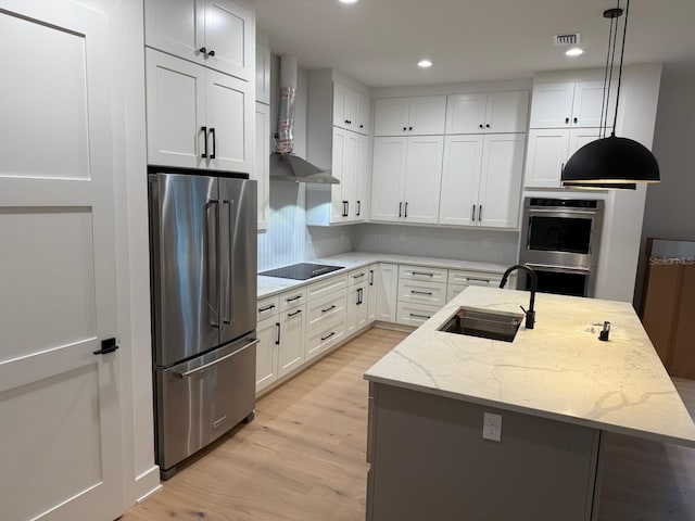 418 W Frances Ave Unit 2, Tampa, FL 33602 - kitchen with appliances with stainless steel finishes, wall chimney range hood, a sink, light wood finished floors, and light stone countertops