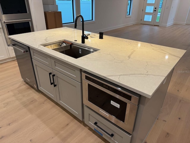 418 W Frances Ave Unit 2, Tampa, FL 33602 - kitchen featuring an island with sink, light wood finished floors, a sink, stainless steel appliances, and gray cabinetry