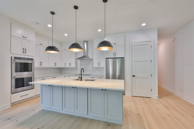 418 W Frances Ave Unit 2, Tampa, FL 33602 - kitchen featuring wall chimney exhaust hood, stainless steel appliances, light wood-type flooring, baseboards, and white cabinets
