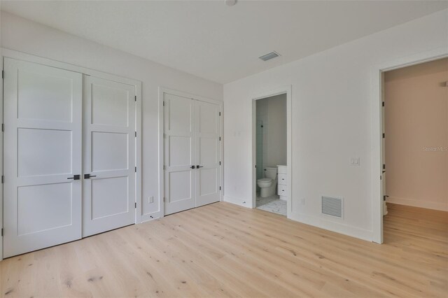 418 W Frances Ave Unit 2, Tampa, FL 33602 - unfurnished bedroom featuring wood finished floors, baseboards, two closets, and ensuite bathroom