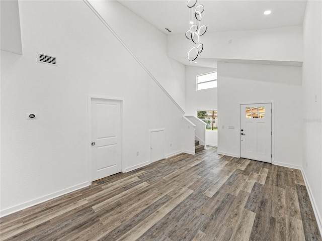 foyer featuring wood finished floors, baseboards, visible vents, high vaulted ceiling, and stairs