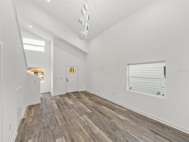 foyer entrance featuring baseboards, high vaulted ceiling, and wood finished floors