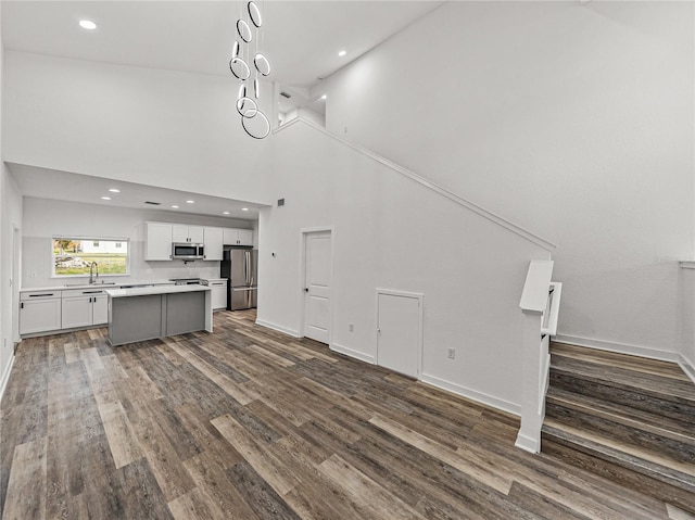 kitchen with a center island, dark wood-type flooring, open floor plan, stainless steel appliances, and white cabinetry