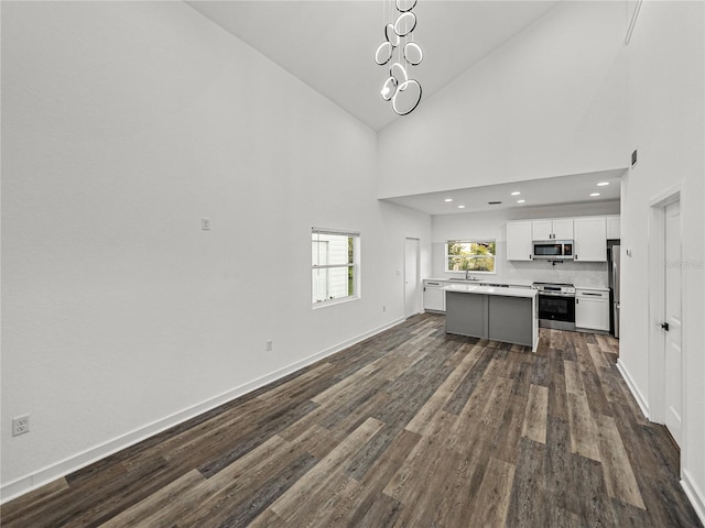 kitchen featuring a center island, light countertops, appliances with stainless steel finishes, white cabinets, and dark wood-style flooring