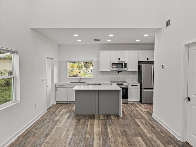 kitchen featuring white cabinets, appliances with stainless steel finishes, light countertops, and dark wood-type flooring