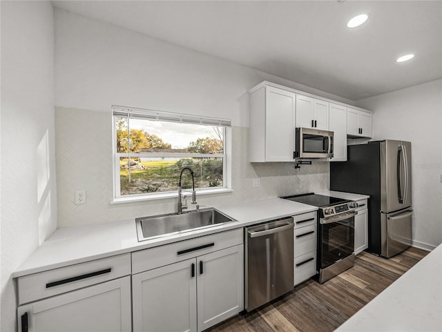 kitchen with backsplash, dark wood-type flooring, light countertops, stainless steel appliances, and a sink