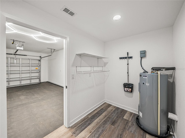 interior space featuring visible vents, baseboards, water heater, a garage, and wood finished floors