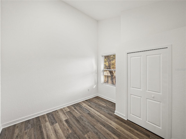 empty room featuring dark wood-type flooring and baseboards