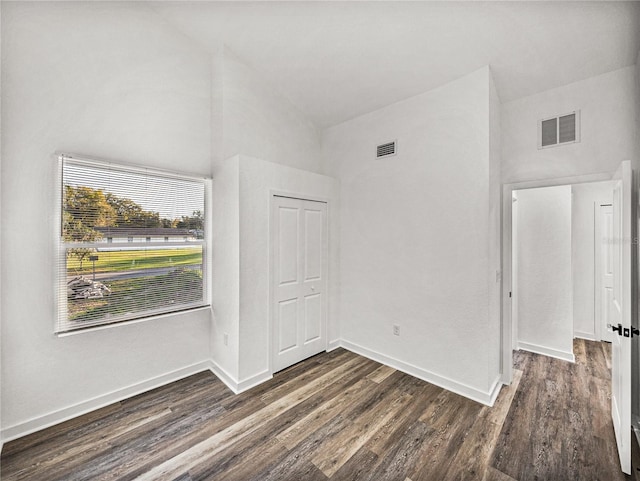 unfurnished bedroom featuring visible vents, high vaulted ceiling, and dark wood finished floors