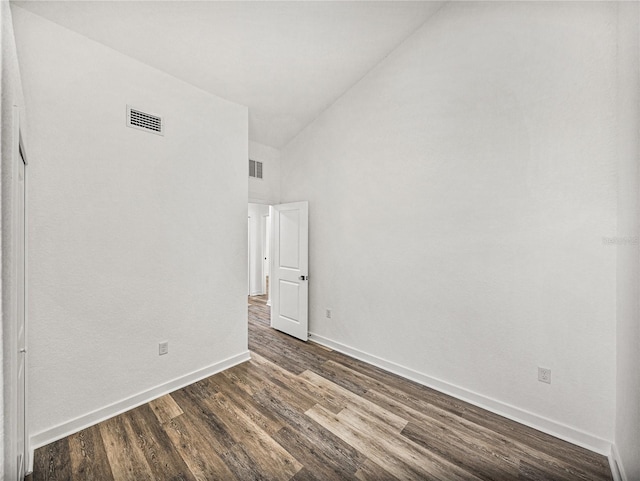 unfurnished room with visible vents, a high ceiling, dark wood-type flooring, and baseboards