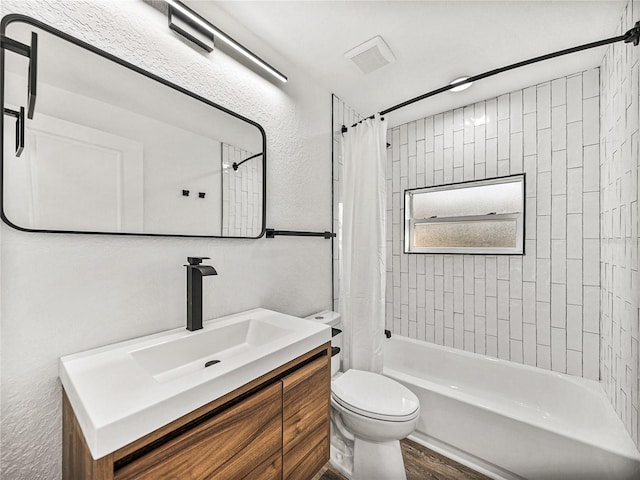 full bath featuring toilet, shower / bath combo, wood finished floors, vanity, and a textured wall