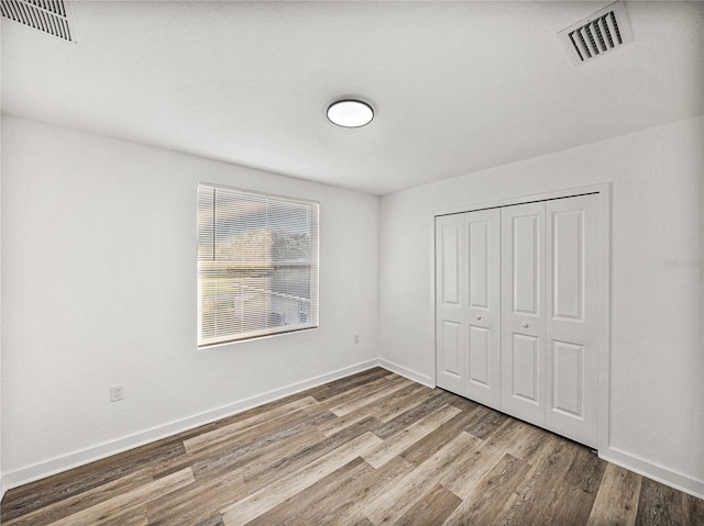 unfurnished bedroom featuring wood finished floors, visible vents, and baseboards