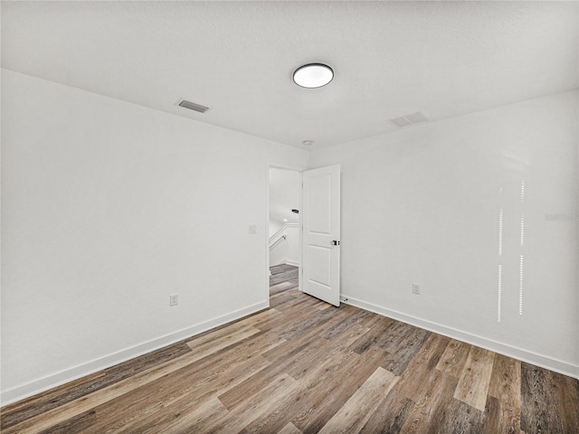 unfurnished room featuring visible vents, baseboards, and wood finished floors