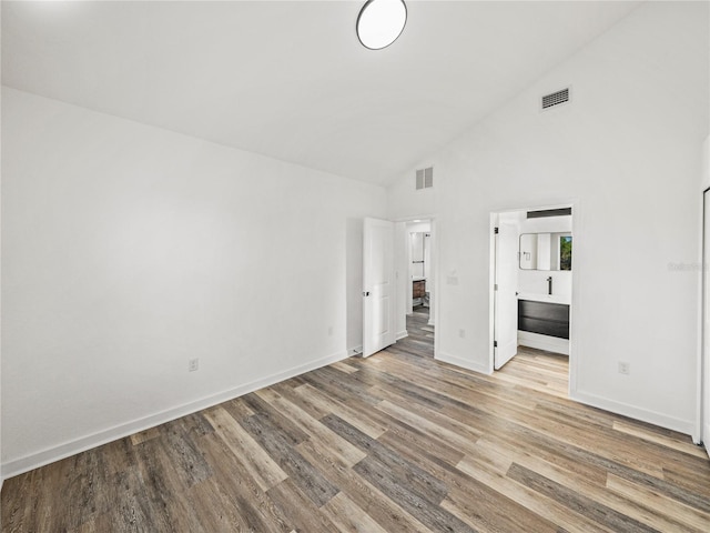 unfurnished bedroom featuring ensuite bath, wood finished floors, visible vents, and baseboards