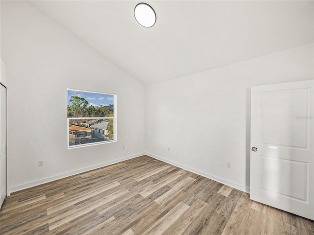 unfurnished bedroom featuring vaulted ceiling, baseboards, and light wood finished floors