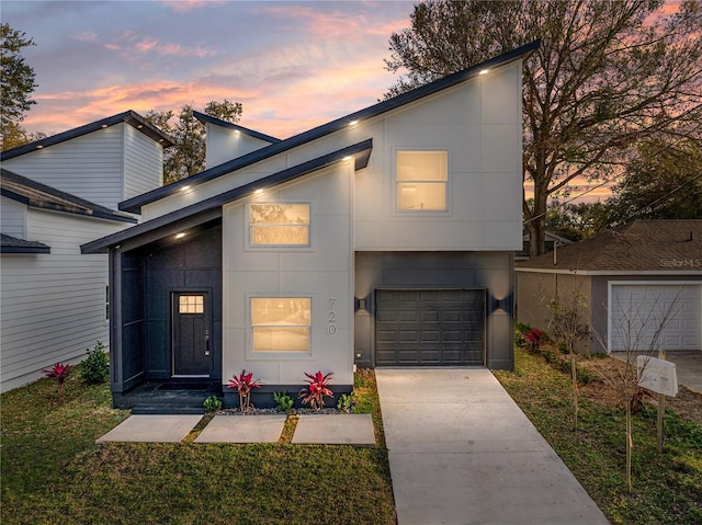 contemporary home with stucco siding, a garage, concrete driveway, and a front yard