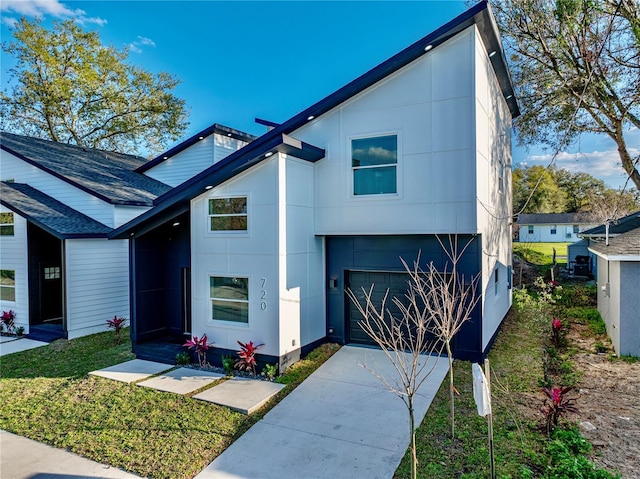 modern home with a garage, a front yard, driveway, and stucco siding