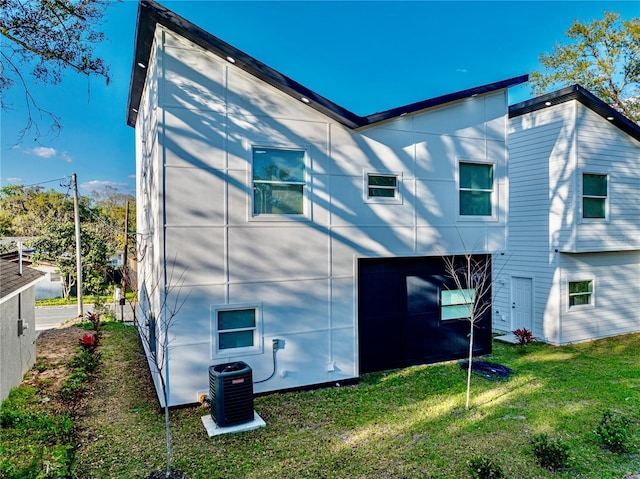 back of property with a yard and central AC