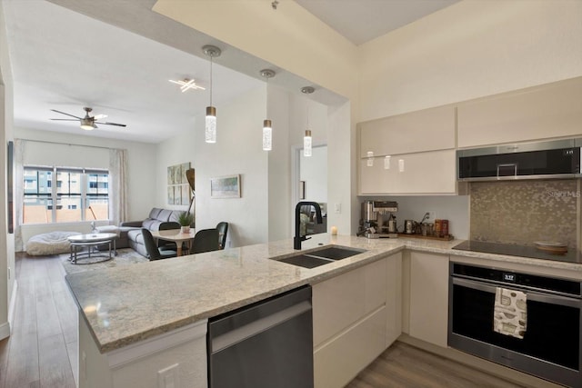 kitchen with dark wood finished floors, decorative backsplash, appliances with stainless steel finishes, a sink, and a peninsula