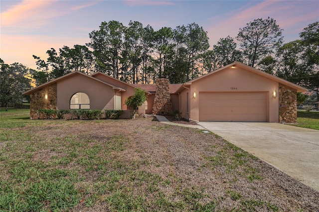 view of front facade featuring a yard, a chimney, stucco siding, concrete driveway, and a garage