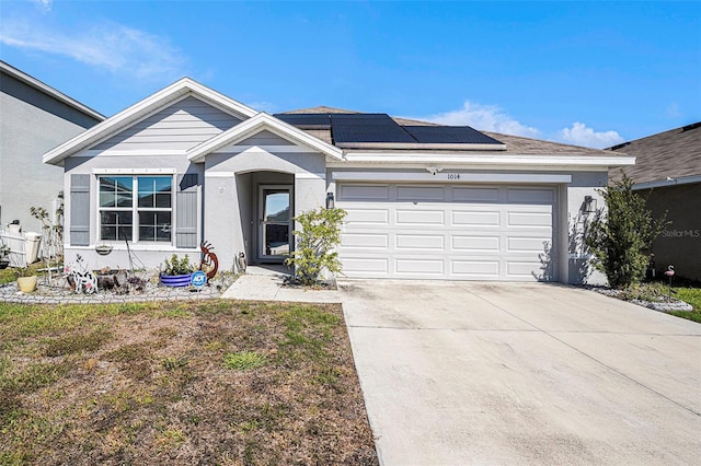 single story home featuring an attached garage, roof mounted solar panels, concrete driveway, and stucco siding