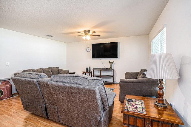 living room with visible vents, a textured ceiling, a ceiling fan, and light wood-style floors