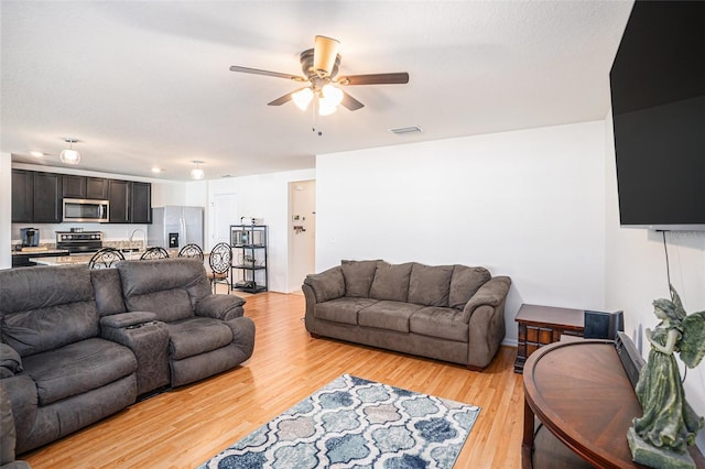 living area with visible vents, ceiling fan, light wood-style flooring, and baseboards