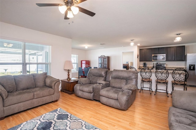 living room featuring light wood-style floors and a ceiling fan