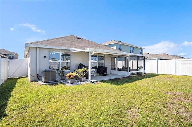 back of house featuring central AC unit, a fenced backyard, a sunroom, a lawn, and stucco siding