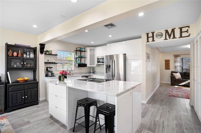 kitchen featuring light wood-style flooring, stainless steel appliances, visible vents, white cabinetry, and open shelves